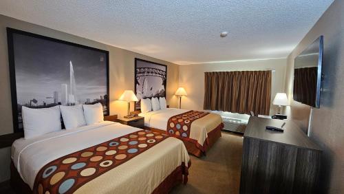 a hotel room with two beds and a television at Super 8 by Wyndham Elgin in Elgin