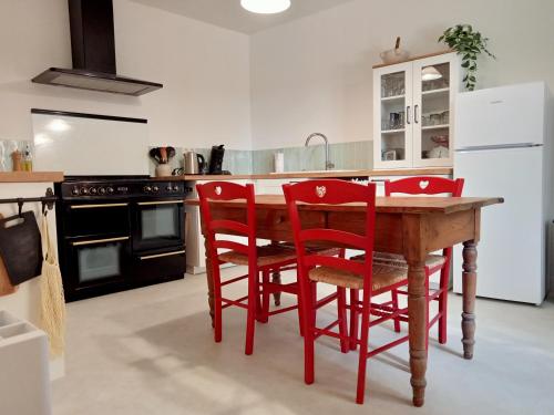 une cuisine avec une table en bois et des chaises rouges dans l'établissement A Cèdre de mon enfance, à Vers-Pont-du-Gard