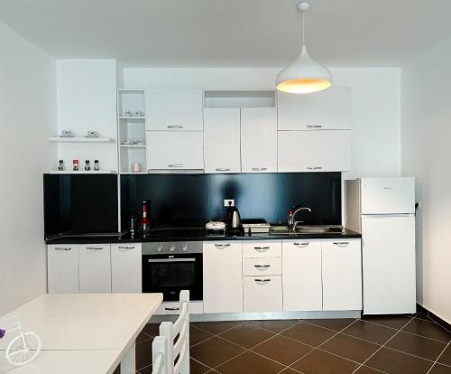 eine Küche mit weißen Schränken und einer schwarzen Wand in der Unterkunft Sea View Apartments in Durrës