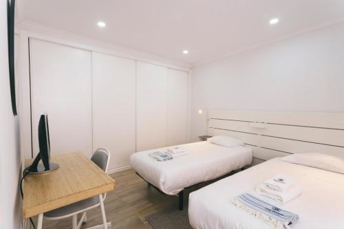 a room with two beds and a desk with a tv at Best Houses 102 - Hut Spot Peniche in Peniche