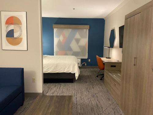 a hotel room with a bed and a desk and a bedroom at Holiday Inn Express & Suites Elyria by IHG in Elyria