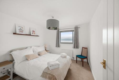 - une chambre blanche avec un lit et une chaise dans l'établissement Marine parade apartment with river view, à Dundee