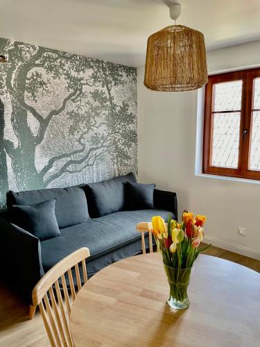 a living room with a couch and a table with flowers at L'Adresse - Rempart Sud - Eguisheim avec garage privé in Eguisheim
