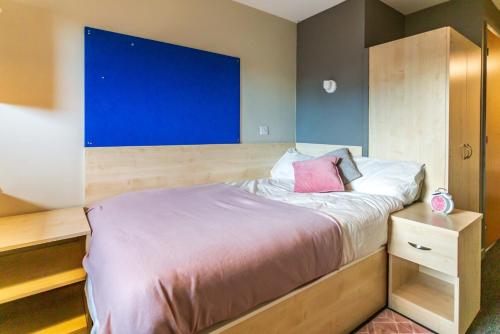 Schlafzimmer mit einem Bett mit blauer Wand in der Unterkunft For Students Only Private Ensuite Rooms with Shared Kitchen at Pittrodrie Street in Aberdeen