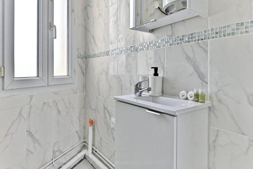 une salle de bain blanche avec un lavabo et une fenêtre dans l'établissement Séjour paisible 4 personnes Banlieue Parisienne, à Gagny