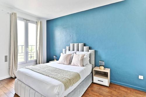 une chambre avec un grand lit avec un mur bleu dans l'établissement Séjour paisible 4 personnes Banlieue Parisienne, à Gagny