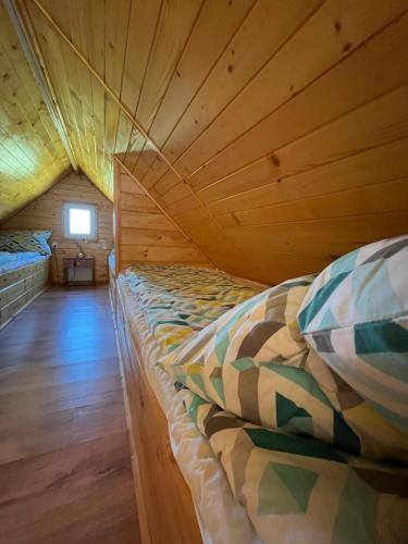 a bed in a room with a wooden ceiling at Siedlik Agroturystyka - spokojne miejsce dla Ciebie i Twojej rodziny in Lidzbark