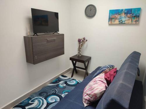a living room with a blue couch and a tv at Casa confort nueva Cerca de outlets y Hospital Regional in Santa Gertrudis