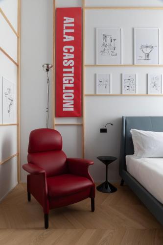 a red chair in a room next to a bed at Interno Marche Design Experience Hotel in Tolentino
