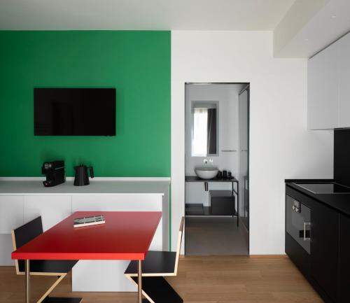 sala de estar con mesa roja y pared verde en Interno Marche Design Experience Hotel, en Tolentino