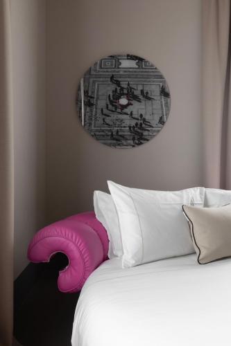 a white bed with a pink pillow next to some pillows at Interno Marche Design Experience Hotel in Tolentino