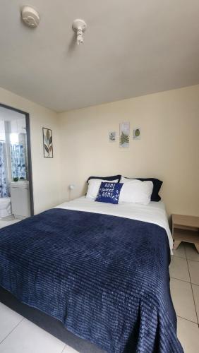 a bedroom with a large bed with a blue blanket at Quédate con sulay habitación a 5mint del aeropuerto in Ciudad Radial