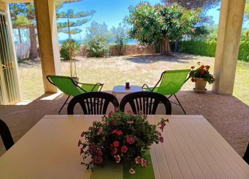 una mesa y sillas con flores en el patio en Casa Panarea - Villetta indipendente sul mare, en Marina di Modica
