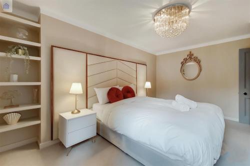 - une chambre avec un grand lit blanc et un lustre dans l'établissement The Shepherd Residence, à Londres