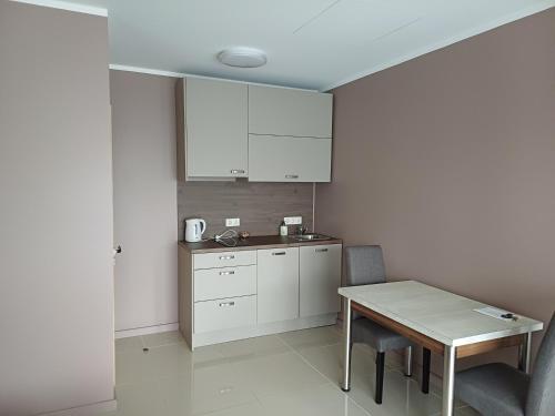 a kitchen with a table and a white cabinet at Lambertu ielas rezidence in Mārupe