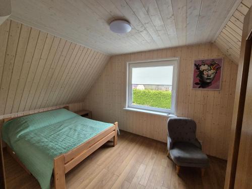 a bedroom with a bed and a window and a chair at Namas Zarasuose su vyno rūsiu in Zarasai
