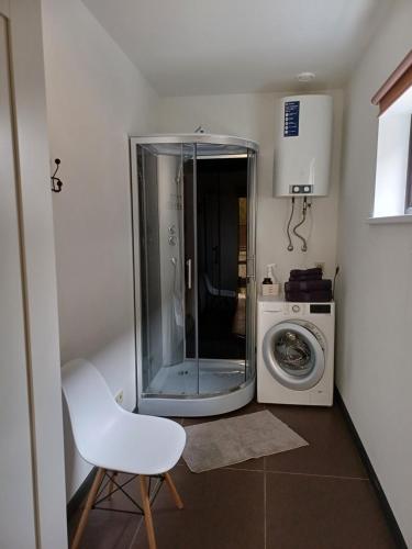 a bathroom with a washing machine and a white chair at Lambertu ielas rezidence in Mārupe