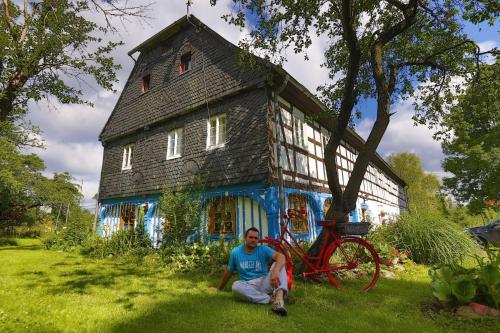 a man sitting in the grass in front of a house at Gesamtes Ferienhaus in Wolimierz mit Offenem Kamin in Świeradów-Zdrój