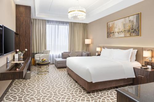 a bedroom with a large bed and a living room at Nivel Hotel in Khamis Mushayt