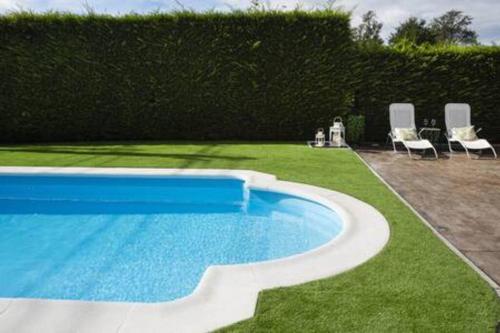 a swimming pool in a yard with chairs next to it at Apartamento con Piscina Ribadumia in Ribadumia