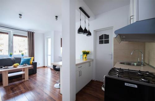 a kitchen and living room with a stove and a couch at Apartament 1 blisko Atlas Areny, ZOO oraz Orientarium in Łódź