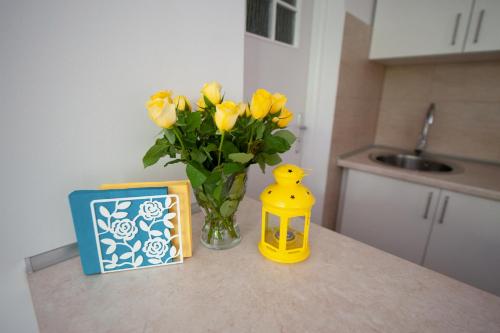 a vase of yellow flowers sitting on a counter next to a box at Apartament 1 blisko Atlas Areny, ZOO oraz Orientarium in Łódź