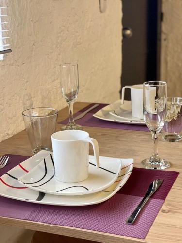 a table with two plates and cups and wine glasses at Súper Apartamento central en Casa Colonial Bogotá in Bogotá