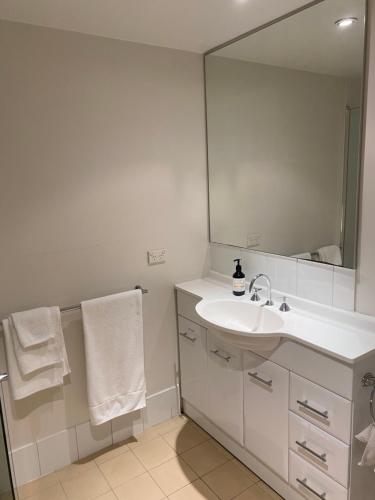Un baño blanco con lavabo y espejo. en Broadways Best, en Sídney