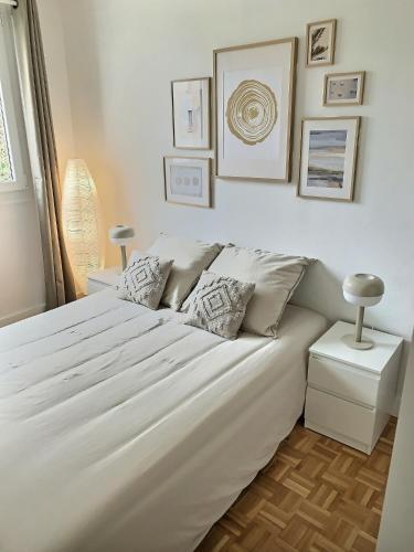 - une chambre dotée d'un grand lit blanc avec des photos sur le mur dans l'établissement Appartement cosy Thiais - Proche Paris et Orly Aéroport, à Thiais