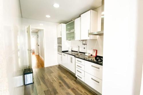 a kitchen with white cabinets and a wooden floor at HU2i - In&Out Sete Rios in Lisbon