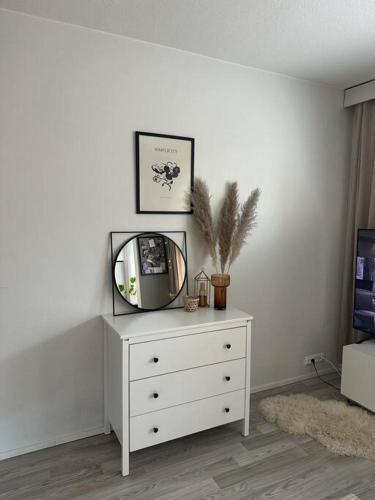 a white dresser with a mirror on top of it at Stunning city center studio with balcony 37 m2 in Lappeenranta