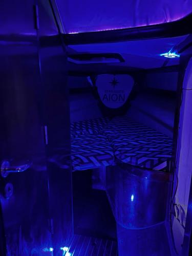 a bed in a room with blue and purple lights at Star Guide AION in Izola