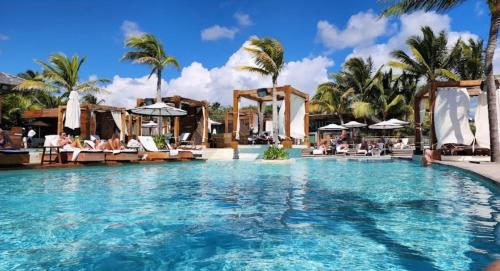 a swimming pool at a resort with palm trees at Vidanta Riviera Maya in Puerto Morelos