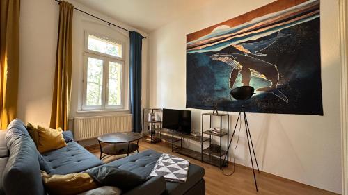 una sala de estar con un sofá azul y una pintura en MiCasa TuCasa - Gemütliche und stilvolle 2-R Wohnung am Steintor, en Halle an der Saale