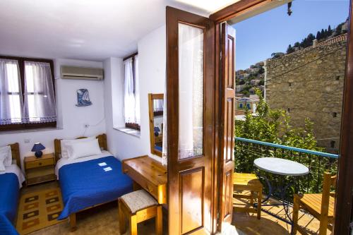 a bedroom with a bed and a balcony with a table at Symi Center Hotel in Symi