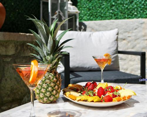 une assiette de fruits sur une table avec deux verres dans l'établissement Lulja Alaçatı - Adults Only, à Izmir