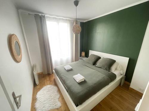 - une chambre avec un grand lit aux murs verts dans l'établissement Appartement chaleureux proche Paris JO 2024, à Saint-Gratien