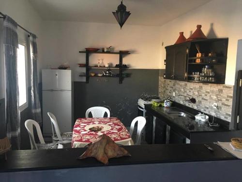 a kitchen with a table and chairs and a refrigerator at lovly imssounae appartment in Imsouane