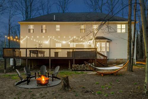 a house with a deck with a fire pit and a hammock at Boho Haven Hideaway - Walk to Pool,Theater,Arcades, Firepit, Lake Access in Thornhurst