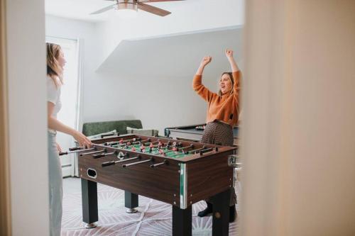 two women standing in a room with a foosball at Boho Haven Hideaway - Walk to Pool,Theater,Arcades, Firepit, Lake Access in Thornhurst