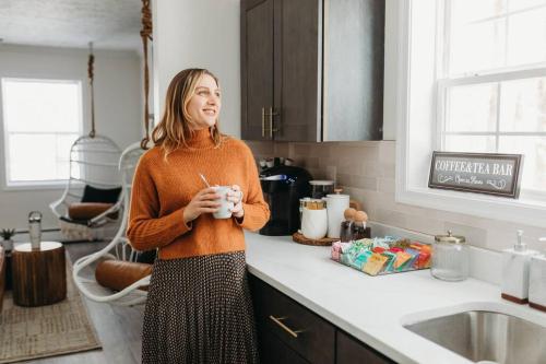 a woman standing in a kitchen holding a drink at Boho Haven Hideaway - Walk to Pool,Theater,Arcades, Firepit, Lake Access in Thornhurst