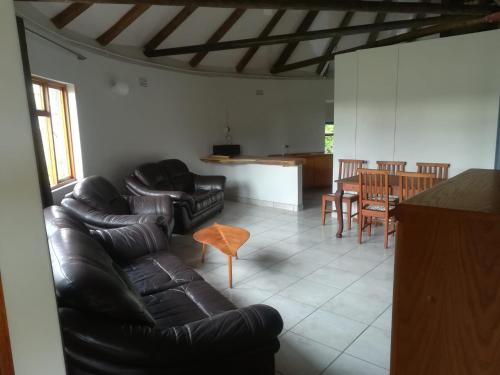 a living room with a leather couch and a table at Die Uil Nes Self Catering Accommodation in Gouritzmond