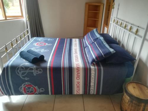 a bed with a blanket on top of it at Die Uil Nes Self Catering Accommodation in Gouritzmond