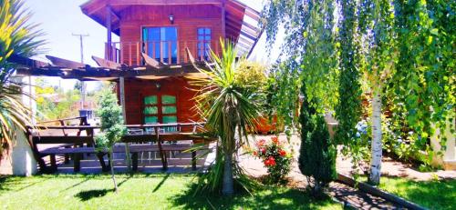 a house with a balcony and a yard with trees at Cabañas con Tinaja 4 a 6 personas in Quillón