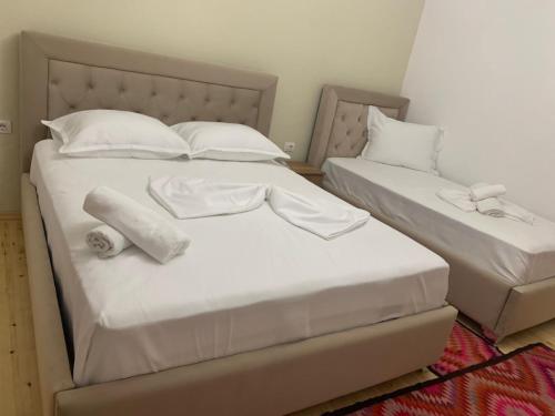 - 2 lits dans une chambre avec des draps et des oreillers blancs dans l'établissement City Center apartments, à Përmet