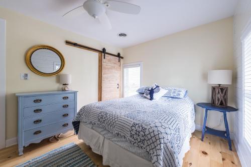 a bedroom with a bed with a blue dresser and a mirror at Summer Haven- Walk to beach & Town from this 4 bedroom 2 bath Coastal Cottage in South Haven