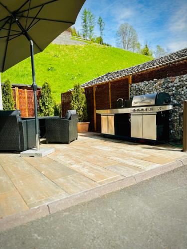a patio with an outdoor grill and an umbrella at PHILSON Apartments in Saalbach Hinterglemm