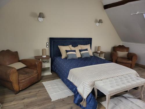 a bedroom with a blue bed and two chairs at Gite Le Charme in Cinais