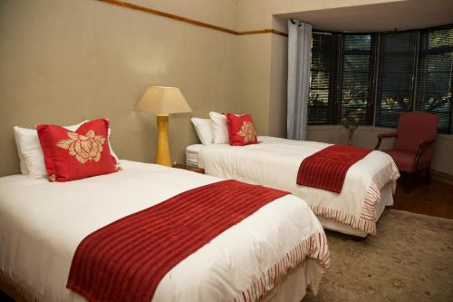 a hotel room with two beds with red pillows at Grootvallei Guest Farm - Main lodge in Boshof
