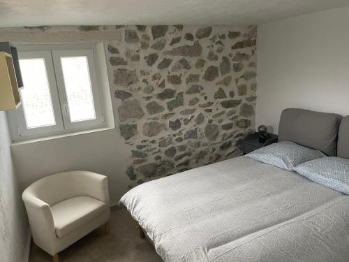 um quarto com uma cama, uma cadeira e uma janela em maison de caractère em Peyroules